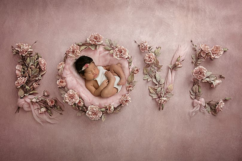 baby laying on a pink background that spells love