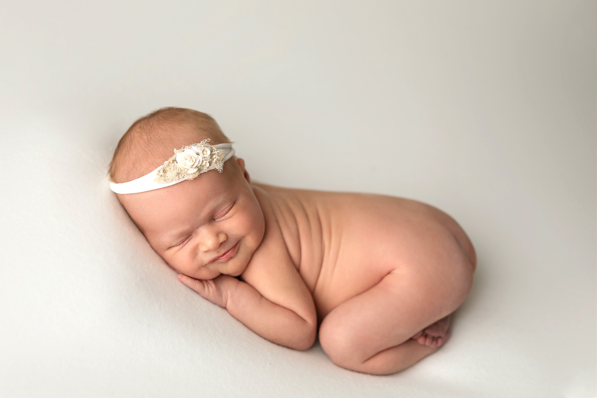 baby girl laying on cream backdrop