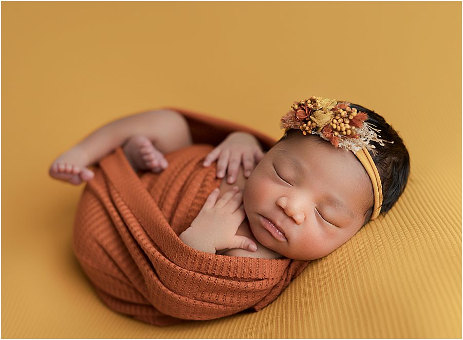 baby girl wrapped in rust color swaddle