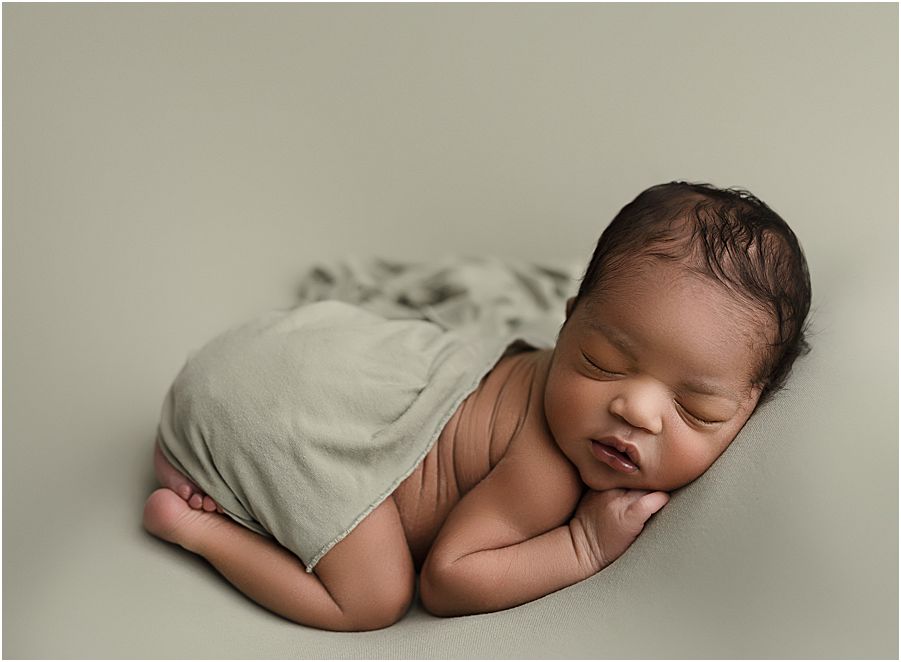 baby boy laying down on green background and green swaddle
