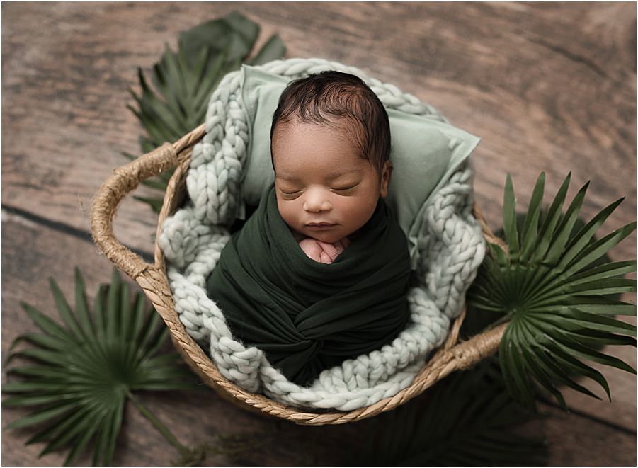 baby wrapped in green, with leaves around